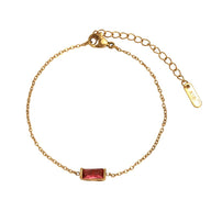 Bracelet fin en titane avec pierre rectangulaire rouge et chaîne réglable dorée.