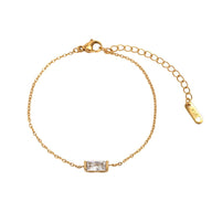 Bracelet fin en titane doré avec pierre rectangulaire transparente, chaîne délicate et fermoir ajustable.