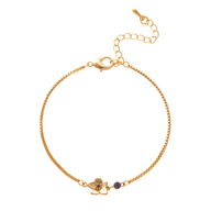 Bracelet fin en titane doré avec petite fleur et pierre bleue d’anniversaire.