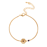 Bracelet fin en titane doré avec fleur sculptée et petite pierre bleue sur chaîne délicate.