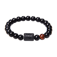 Bracelet perles rondes noires en verre avec symbole astrologique en rectangle noir et perle marron rougeâtre.