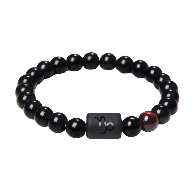 Bracelet perles rondes en verre noir avec perle cylindrique matte gravée du symbole astrologique Capricorne, accent marron.