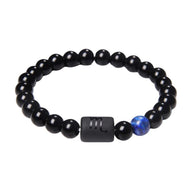 Bracelet perles de verre noir brillant avec perle bleue et symbole scorpion gravé sur une perle rectangulaire noire mate.