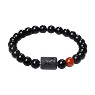 Bracelet composé de perles de verre noir rondes avec une perle plate gravée du symbole astrologique Sagittaire et une perle.