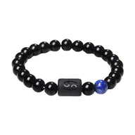 Bracelet en perles de verre noir avec perle bleue et carré noir gravé du symbole astrologique Cancer.