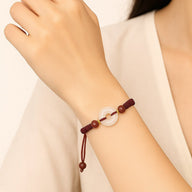 Bracelet porte-bonheur bordeaux en fil ciré avec pierre ronde de jade translucide et perles de cinabre rouge.