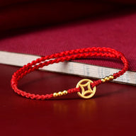 Bracelet en nylon fil rouge tressé avec pendentif doré orné de perles dorées, style élégant et minimaliste.