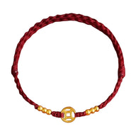 Bracelet porte-bonheur en nylon fil rouge tressé avec perles dorées et breloque centrale dorée ajourée.