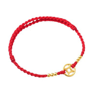 Bracelet porte-bonheur en fil rouge tressé avec perles dorées et charm en forme de V doré.