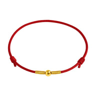 Bracelet porte-bonheur en fil rouge nylon avec perle dorée centrale et nœuds coulissants.