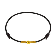 Bracelet porte-bonheur en nylon noir avec perle dorée centrale et fermoirs assortis.