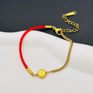 Bracelet femme en fil rouge tressé et chaîne en titane doré avec médaillon gravé et fermoir mousqueton.