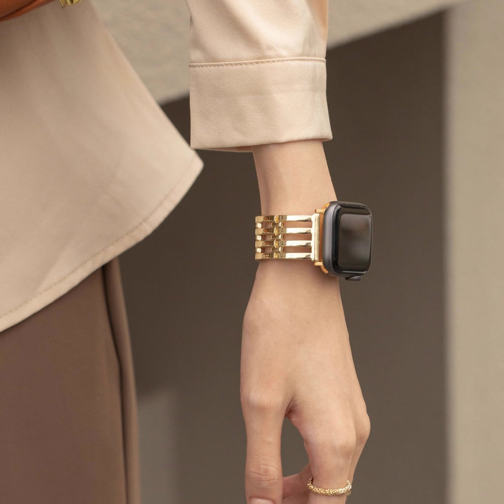 Bracelet or chic à maillons pour Apple Watch porté au poignet féminin, style soirée élégant.