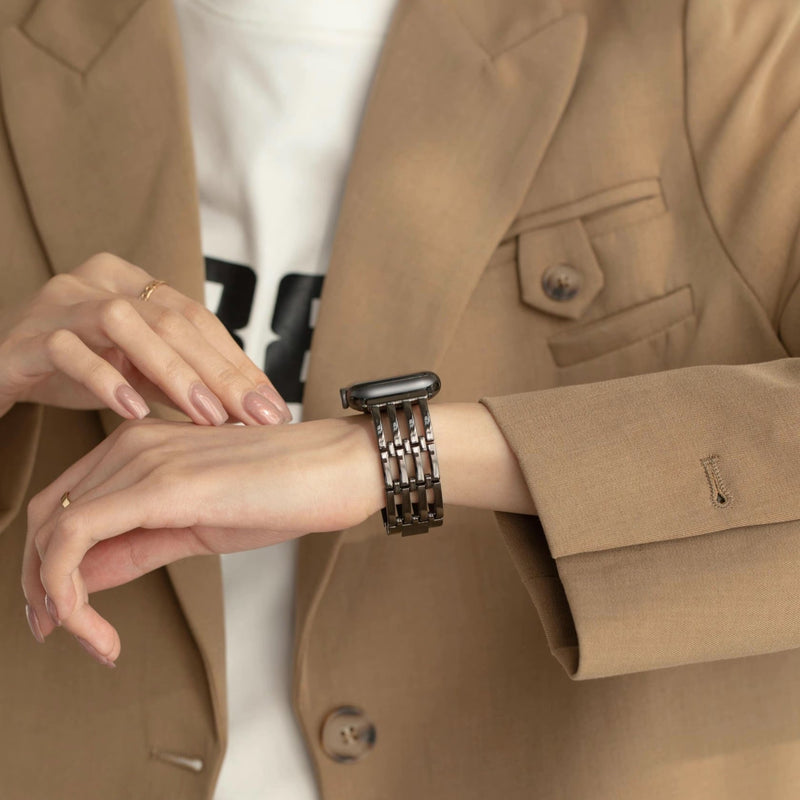 Bracelet Apple Watch noir en maille métallique élégante porté avec veste beige chic.