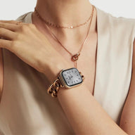 Bracelet mailles cubaines en acier inoxydable doré, ajustable, porté avec Apple Watch argentée sur poignet féminin.