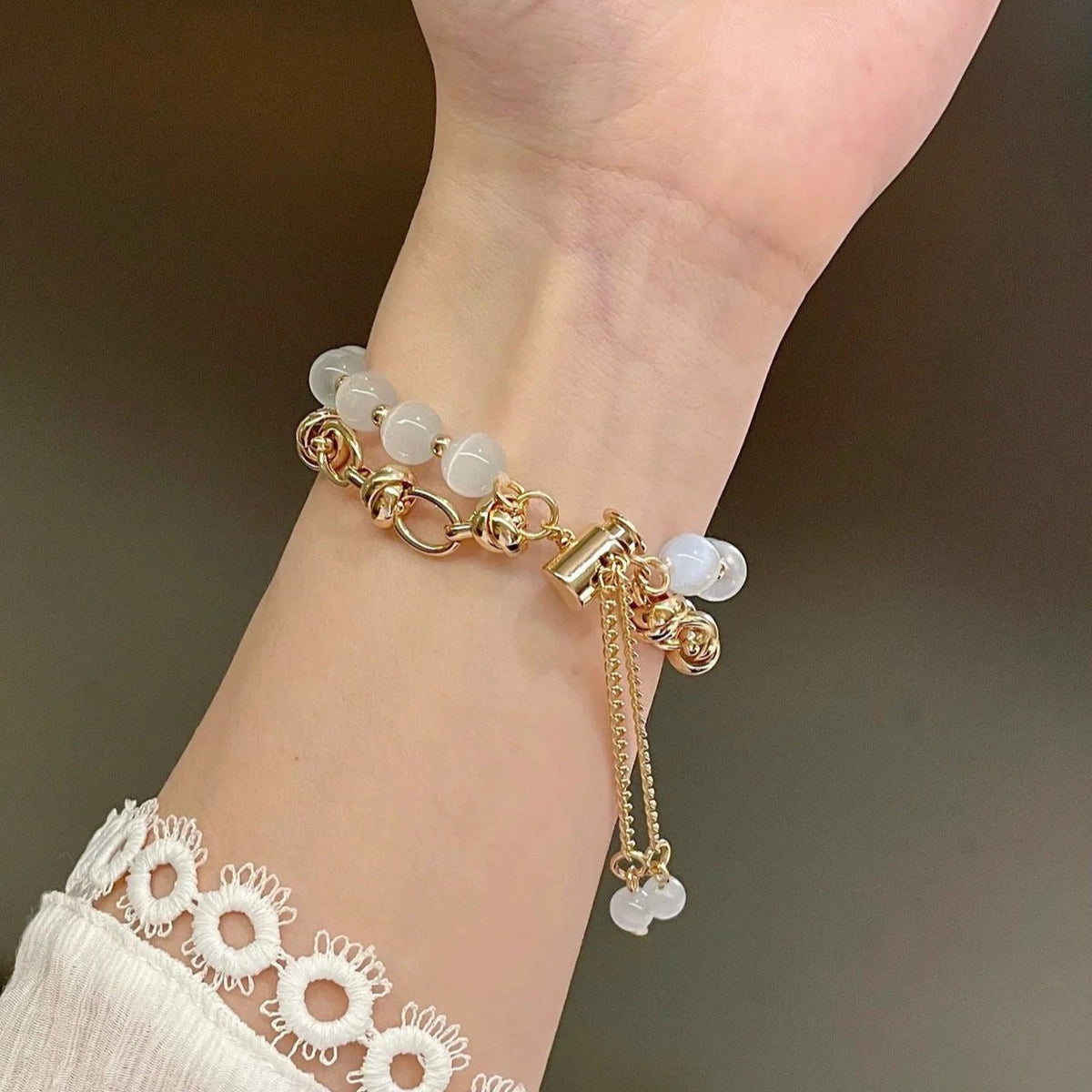 Bracelet pour Apple Watch en perles œil de chat blanches avec chaînes et fermoir doré élégant ajustable.