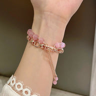 Bracelet Apple Watch perles œil de chat roses et chaîne dorée rosée, ajustable sur poignet féminin.