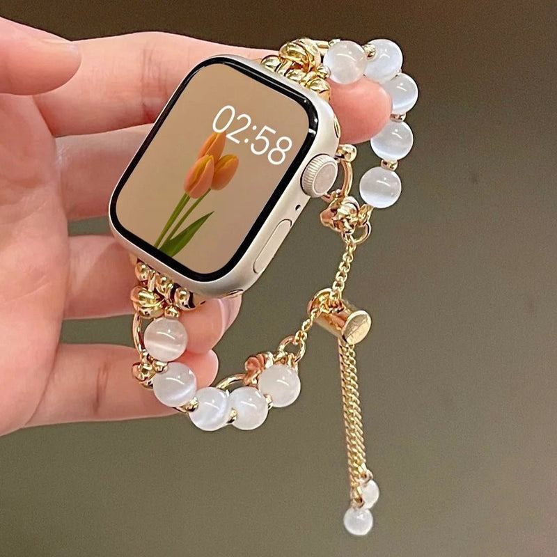 Bracelet pour Apple Watch en perles œil de chat blanches avec détails dorés et fermoir réglable.