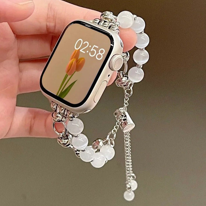 Bracelet ajustable pour Apple Watch en perles œil de chat blanches avec chaîne argentée fine et breloque en forme de cœur.