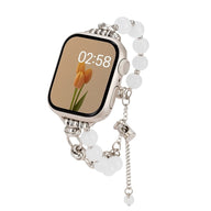 Bracelet Apple Watch en perles œil de chat blanches avec détails argentés et chaînette ajustable.