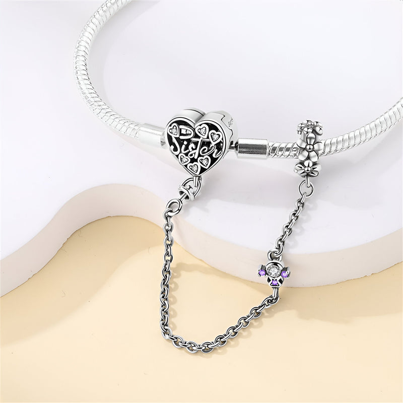 Bracelet argenté pour charm avec cœur gravé et chaîne de sécurité ornée d'un petit pendentif violet.