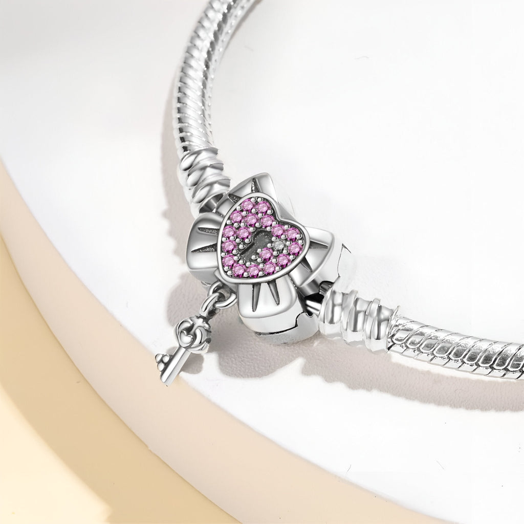 Bracelet argent avec cœur cadenassé orné de petits cristaux roses et clé suspendue.
