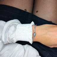 Bracelet argenté fin avec charms en forme de cœur et papillons, style délicat et personnalisable.