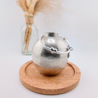 Bracelet argenté fin pour charm avec pendentifs cœur et papillons, style élégant et délicat.