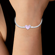 Bracelet argenté fin avec charm en forme de cœur rose lumineux, style élégant et moderne.