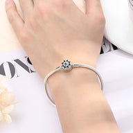Bracelet rigide argenté avec charm étoile ajourée portée au poignet féminin.