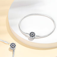Bracelet en argent fin avec un charm rond orné de petites étoiles bleues et blanches, style élégant.