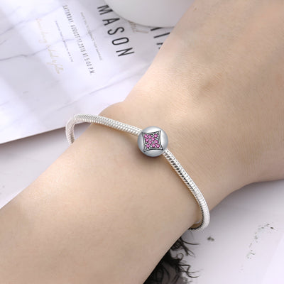 Bracelet argenté fin avec charm carré orné d’une étoile rose au centre, style élégant pour femme.