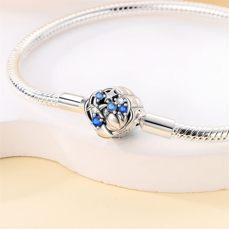 Bracelet pour charm en argent avec fermoir sphérique orné de petites étoiles bleues et détails coquillage.