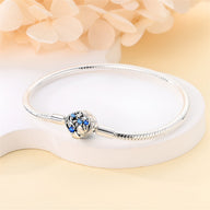 Bracelet charm en argent avec fermoir étoile orné de petites étoiles bleues et coquillage sculpté.