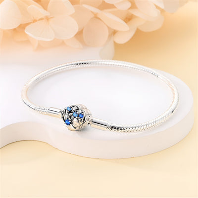 Bracelet charm en argent avec fermoir étoile orné de petites étoiles bleues et coquillage sculpté.