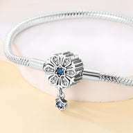 Bracelet argenté avec charm fleur gravée et pierres bleues, pendentif étoile bleue suspendu.