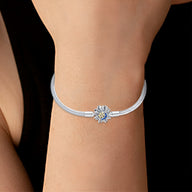 Bracelet argenté pour charm avec pendentif soleil et lune, détail doré et pierre bleue centrale.