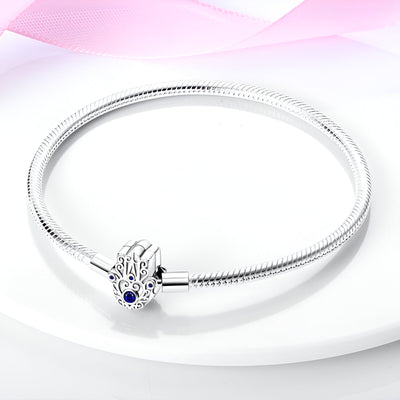 Bracelet argenté pour charms avec pendentif main de fatma orné d’un œil bleu, modèle Mireya.