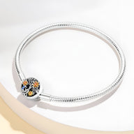 Bracelet en argent 17 cm avec médaillon floral noir orné de fleurs jaunes et blanches.