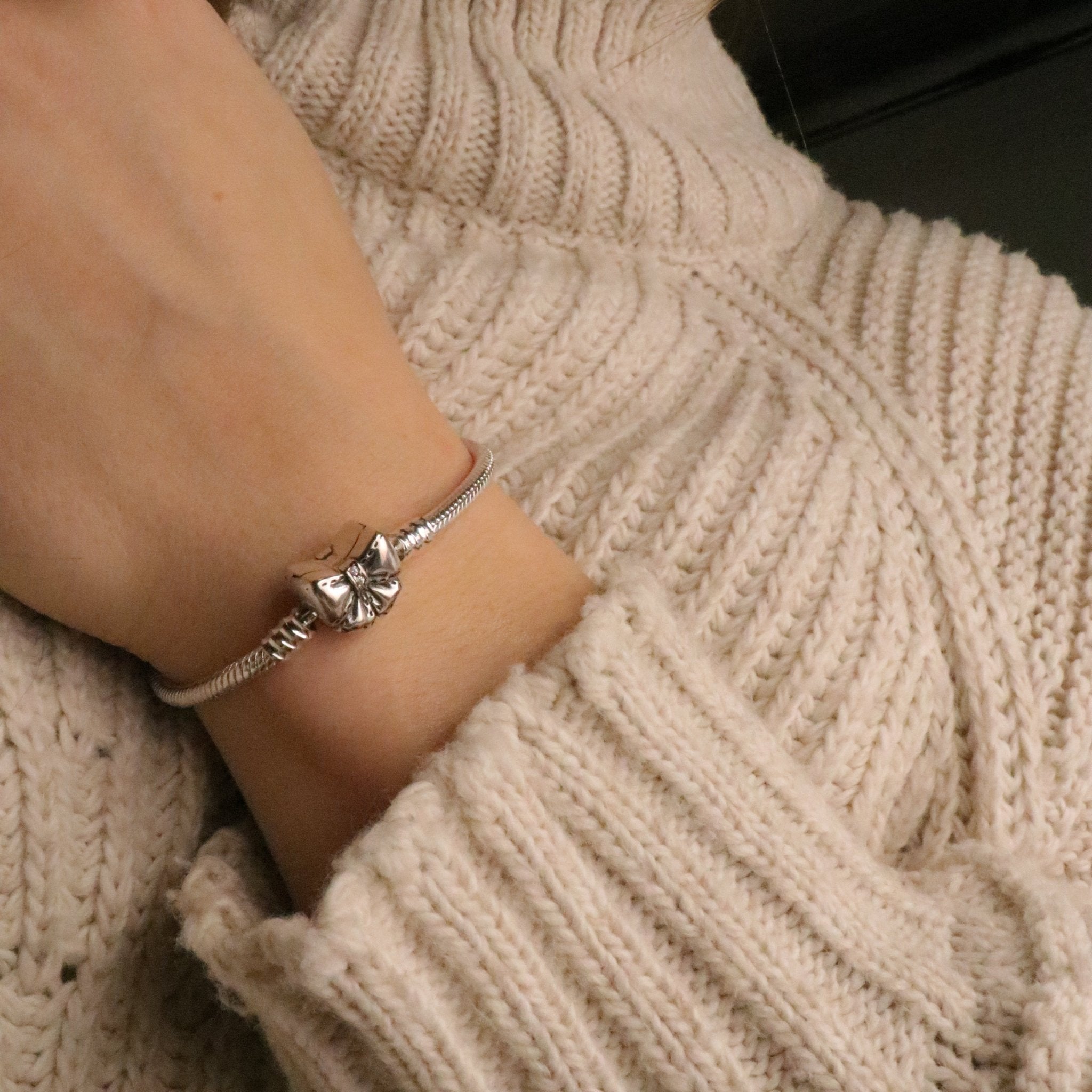 Bracelet fin en cuir beige avec nœud ruban en métal argenté, style délicat pour femme.