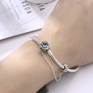 Bracelet argenté fin avec un charm rond orné d'une pierre bleue nuit, style élégant et délicat.
