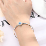 Bracelet argenté fin avec charm œil bleu protecteur, style minimaliste élégant pour femme.