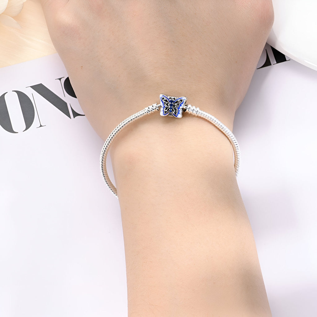 Bracelet en argent fin avec charm papillon bleu délicat, style minimaliste féminin.