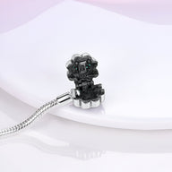 Bracelet en argent avec charm en forme de fleur noire, détail brillant et chaîne serpent fine.