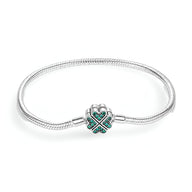 Bracelet argenté serpent avec charm en forme de trèfle orné de pierres vertes.