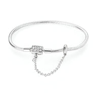 Bracelet argenté fin avec fermoir orné de cristaux et chaîne de sécurité délicate.