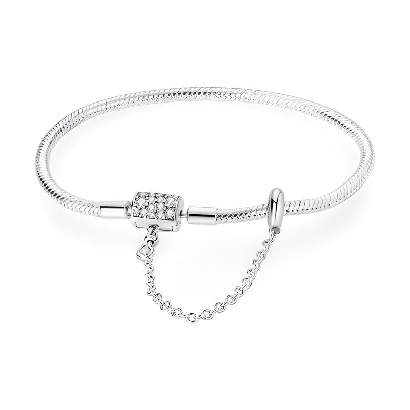 Bracelet argenté fin avec fermoir orné de cristaux et chaîne de sécurité délicate.