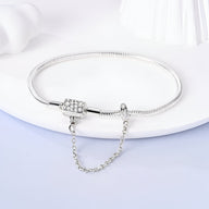 Bracelet pour charm en argent avec chaîne de sécurité et fermoir à motifs gravés.