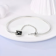 Bracelet serpent argenté fin avec fermoir à vis et chaîne de sécurité élégante.