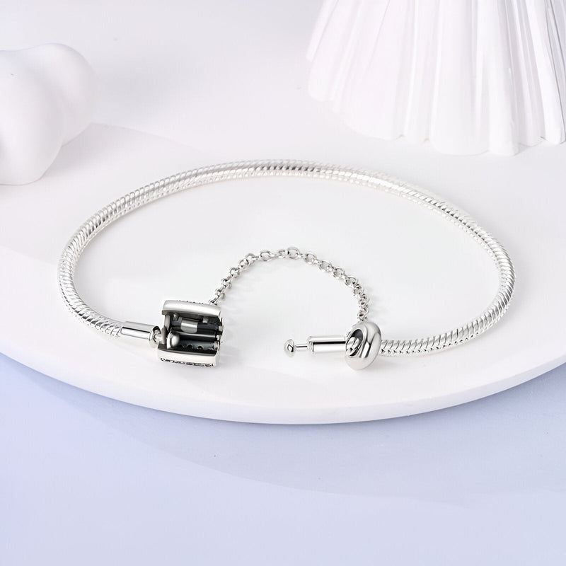 Bracelet serpent argenté fin avec fermoir à vis et chaîne de sécurité élégante.